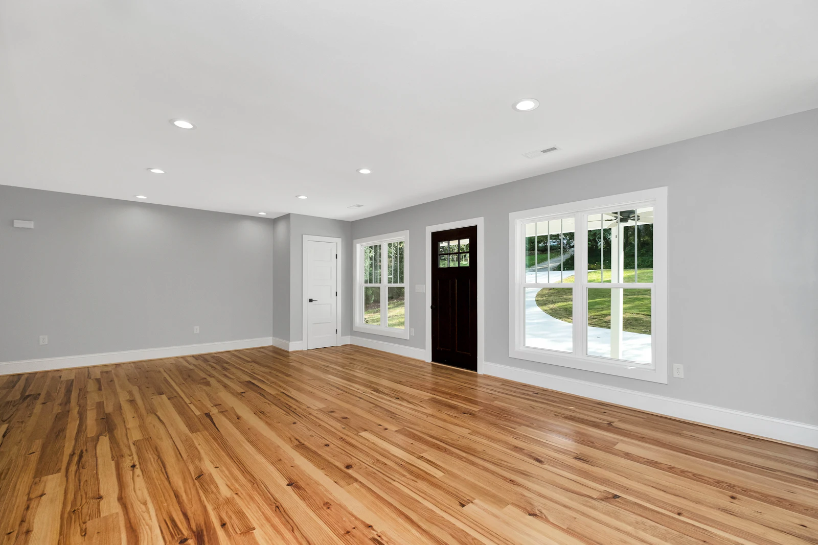 A room with a continuous run of plank flooring and no furniture