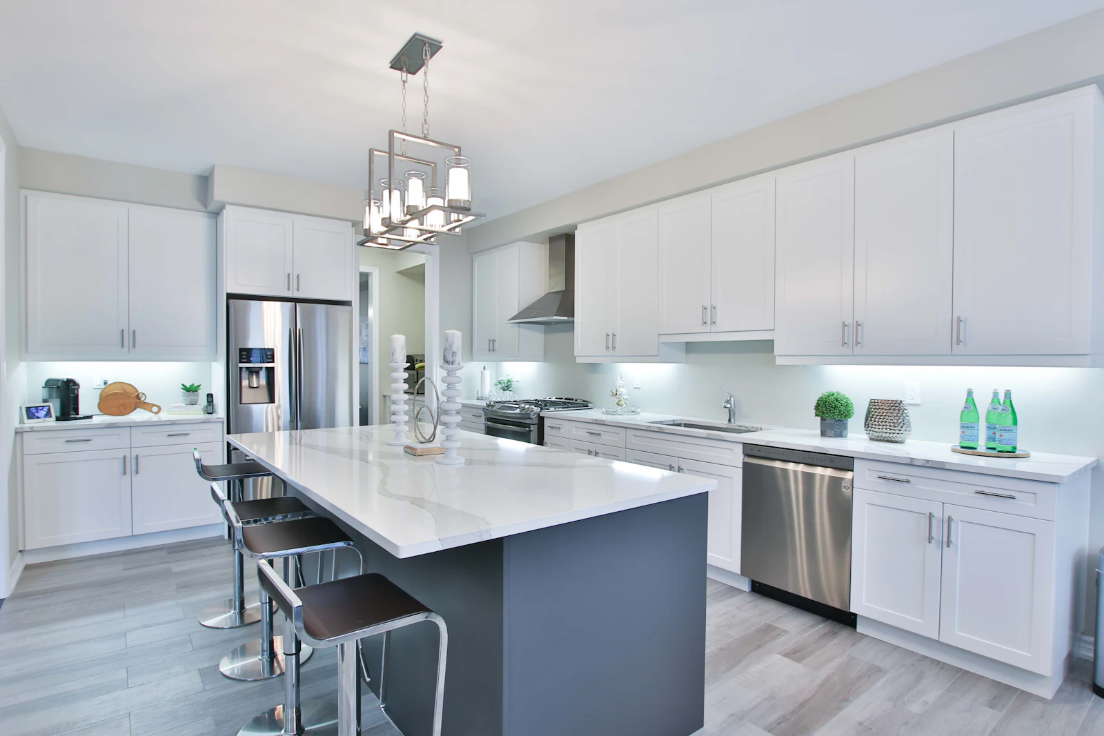 A kitchen with white perimeter cabinets and a dark island with stainless appliances