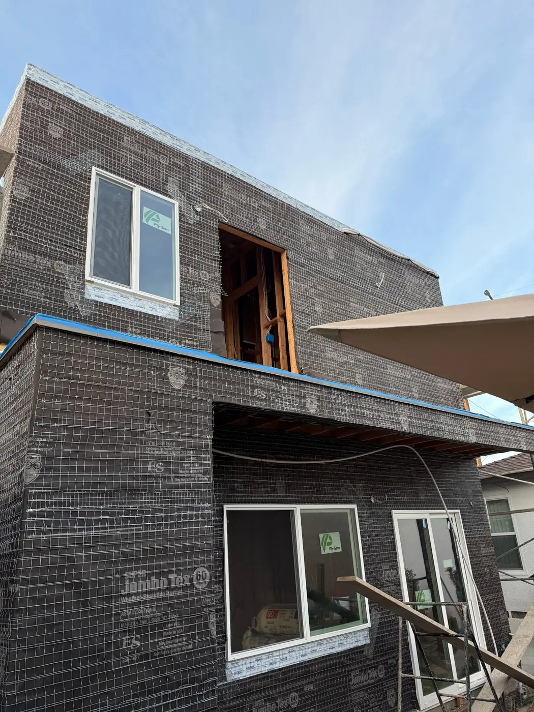 A two-story unit wrapped in building paper and lath with the windows fitted, ready for stucco